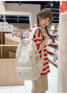Vista detallada de la linda mochila escolar blanco crema con dibujos de osos y estrellas.