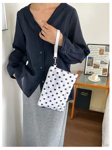 Close-up of a white and black polka dot makeup bag with a wristlet strap.