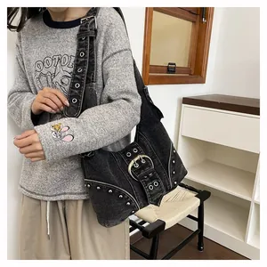 Close-up of black denim shoulder bag with silver rivets and large buckle