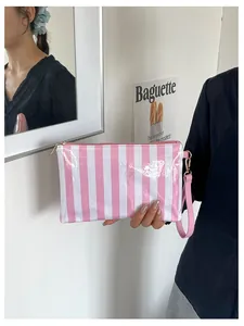 Close-up of a pink and white striped waterproof makeup bag held by a model in lifestyle view