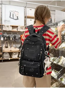 Vista trasera de una niña que lleva una mochila escolar negra grande con patrones de estrellas