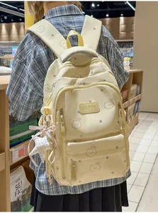 Detalle de mochila crema con estampado de osos, colgante de estrella y parche de cuero