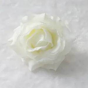 Detailed close-up of a realistic white artificial silk rose flower head on soft fabric