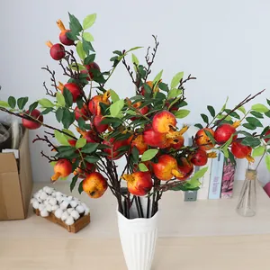 Gros plan détaillé d'une branche de grenade artificielle avec 7 fruits dans un vase blanc