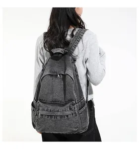 Achteraanzicht van een vintage grijze denim rugzak gedragen door een vrouwelijk model.