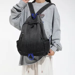 Distressed black denim backpack worn by model for casual travel style details