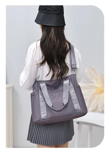 Vista posteriore di una modella con una grande borsa da viaggio viola e cinghie