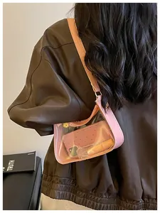 Vue détaillée d'un sac à bandoulière tendance en PVC rose transparent porté à l'épaule.
