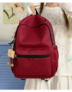 Nahaufnahme eines weinroten High-Street-Rucksacks mit süßem Plüsch-Anhänger für Schüler