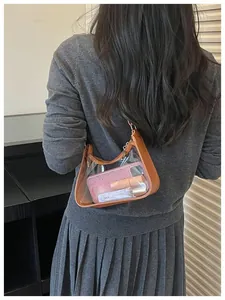 Détail d'un sac sous l'aisselle en PVC transparent montrant les objets du quotidien