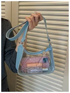 Vue détaillée du sac sous les aisselles en PVC bleu clair transparent tenu à la main avec accessoires.