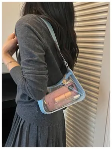 Vue de côté d'un modèle portant un sac sous le bras en PVC transparent bleu clair