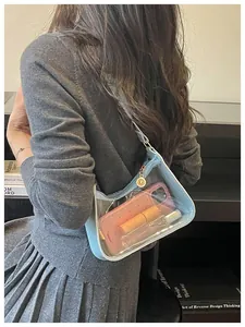 Vue détaillée d'un sac à bandoulière en PVC transparent bleu clair porté par un mannequin.