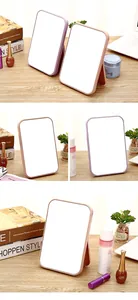 Portable foldable desktop makeup mirror with pink and purple frames on wooden desk