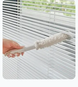 Handheld microfiber brush cleaning dust from white venetian blinds effectively