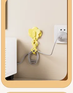 Détail d'un enrouleur de cordon papillon jaune organisant un câble électrique sur un mur.