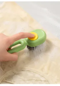 Close-up of a press-to-dispense liquid cleaning brush scrubbing soapy fabric