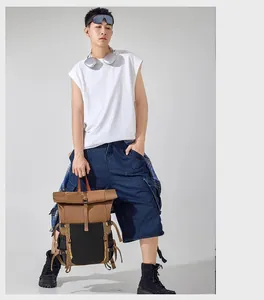 Asian male model posing with a brown and black roll-top tactical outdoor backpack