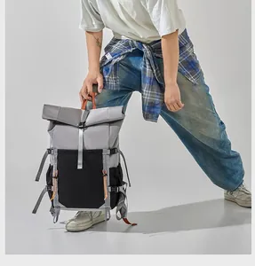 Detailed view of a gray and black roll-top commuter backpack with orange details
