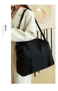 Detailed view of the large black nylon travel bag styled with an elegant outfit