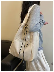 Vue détaillée d'un grand sac à cordon crème porté par un mannequin en tenue décontractée