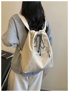 Vue arrière d'une personne portant un sac à dos beige à cordon avec des cordons rayés