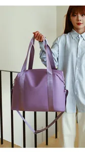 Asian model holding a large purple nylon travel bag with shoulder strap detail