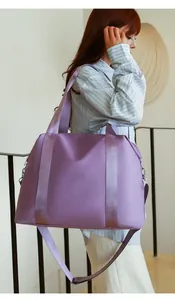 Close-up of a large purple nylon travel bag worn by a model in a minimalist indoor setting