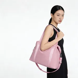 Large pink nylon travel bag with shoulder strap worn by a stylish model