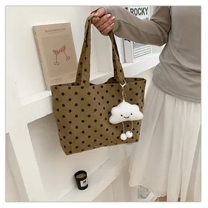 Detaillierte Aufnahme einer braunen gepunkteten Canvas-Tote-Bag mit einem weißen Wolkenanhänger