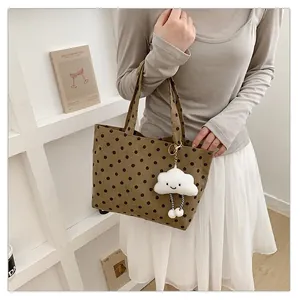 Lifestyle-Ansicht einer braunen gepunkteten Canvas-Tasche mit einem süßen Wolkenanhänger