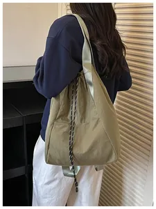 Gros plan d'un sac seau à cordon kaki porté en bandoulière dans un cadre de vie quotidien.