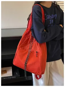 Grand sac à dos à cordon orange porté comme un sac à bandoulière élégant et moderne.