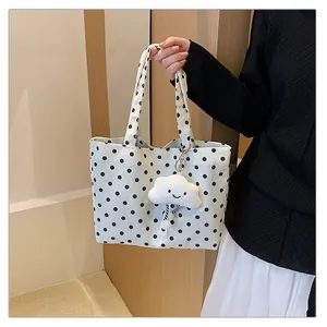 Detailansicht einer weißen Polka-Dot Canvas Tote Bag mit süßem Plüschwolken-Anhänger.