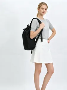 Side view of a woman wearing a black minimalist casual backpack in a bright studio