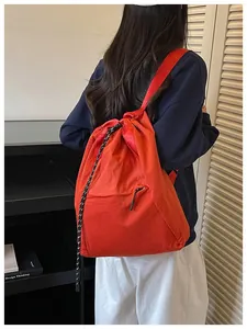 Détail lifestyle d'un sac à dos léger orange vif à cordon de serrage sur le dos du modèle.