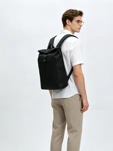 Back view of a man carrying a sleek black roll-top backpack for travel and daily use