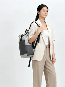 Modern gray roll-top backpack being worn by a female model in a studio setting