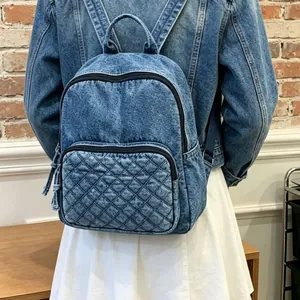 Détail d'un sac à dos en denim matelassé élégant porté avec une veste en jean