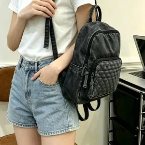 Détail d'un sac à dos en denim noir délavé avec poche matelassée porté par un modèle.