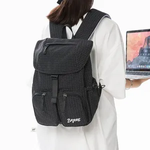 Detailed view of a lightweight black checkered nylon backpack worn by a person