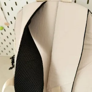 Detail van een lichte beige rugzak met de gewatteerde zwarte mesh schouderriem.