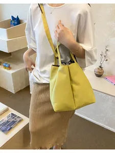 Lifestyle shot of a yellow commuter water bottle carrier bag with a long shoulder strap