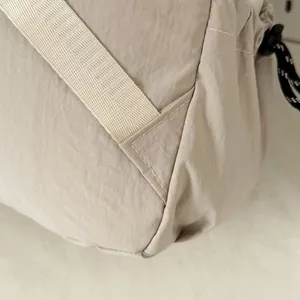 Detail van versterkte stiksels en waterafstotende stof op een beige outdoor wandelrugzak.