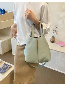 Model carrying a large sage green minimalist tote bag for water bottles and daily use