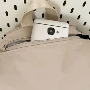 Detailweergave van het bovenste ritsvak van een beige waterbestendige outdoor kampeerrugzak