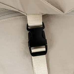 Detailopname van de duurzame zwarte plastic gesp en de beige nylon riem van de rugzak
