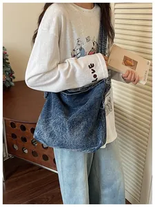 Detail view of casual vintage blue denim crossbody messenger bag worn by female model