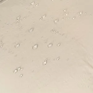 Macro-detail van waterafstotende stof met waterdruppels op beige outdoor rugzak