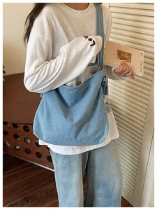 Lifestyle view of a casual blue denim messenger bag worn by a model in a room